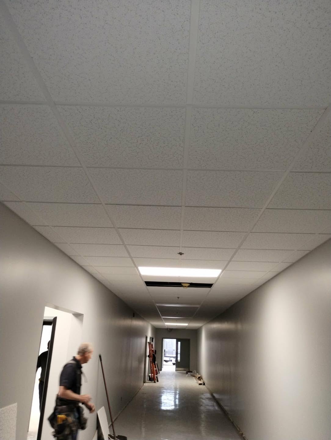 Corridor institutionnel avec plafond suspendu T-bar et tuiles acoustiques fraîchement installés — Descoteaux Acoustique