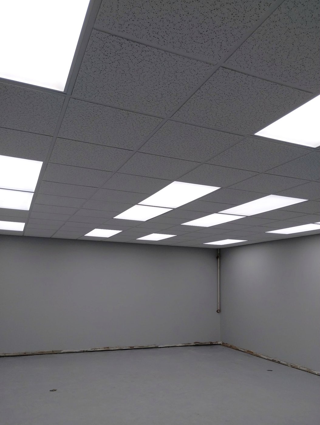 Pièce commerciale vide au plafond suspendu T-bar terminé avec éclairage encastré — Descoteaux Acoustique